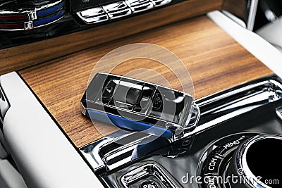 Closeup inside vehicle of wireless blue leather key ignition on natural wood panel. Wireless start engine key. Car key remote isol Stock Photo