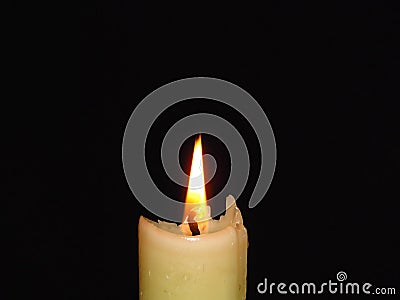 Closeup of an isolated burning candle on dark black background. Flame, light, candle wax. Mystery, religion concept. Stock Photo