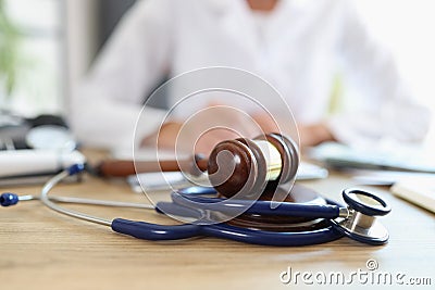 Closeup of judge gavel of stethoscope doctor in background writing notes Stock Photo