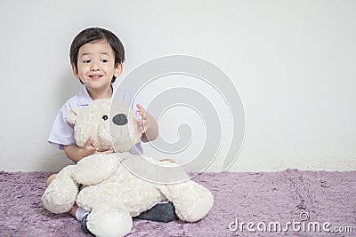 Closeup asian kid with excited face with bear doll sit on carpet with copy space Stock Photo