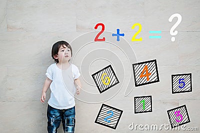 Closeup asian kid look at mathematic question on marble stone wall textured background Stock Photo