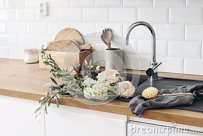 Closeup of kitchen interior. White brick wall, metro tiles, wooden countertops with kitchen utensils. Roses flowers in Stock Photo