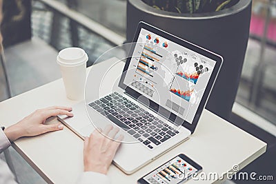 Closeup laptop with graphs, charts, diagrams on screen.On table cup of coffee and smartphone. Stock Photo