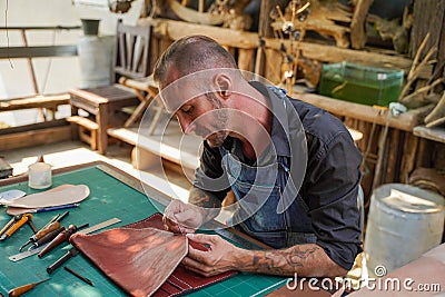 Closeup leather craftsman is carefully to sew a leather bag for a customer. Stock Photo