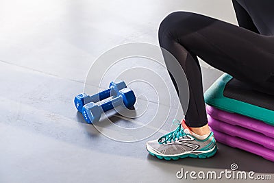 Closeup legs, sneakers,step platform and dumbbells. Woman sit Stock Photo