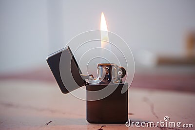 Lighter with flame on wooden table Stock Photo