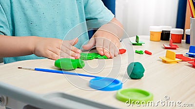 Closeup of little boy forming and shaping colorful plasticine or clay with hands. Special colorful dough for enhancing Stock Photo