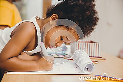 Closeup little child girl black skin writing doing homework at home Stock Photo