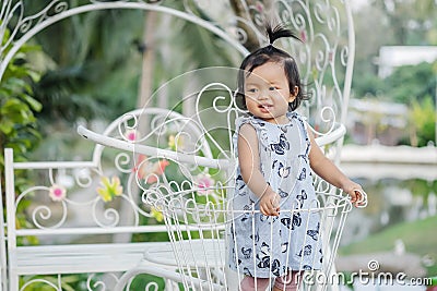 Closeup little girl stand on steel bicycle basket for decorate in the garden background with smile face Stock Photo