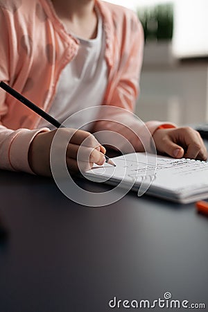 Closeup of little schoolchild writing mathematics homework on notebook Stock Photo