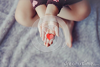 Macro of child with adult parent hands palms holding a bunch of small red and purple paper foam hearts Stock Photo