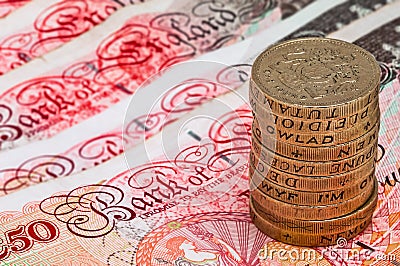 Closeup macro view at UK currency fifty pound banknotes and stack of one pound coins Editorial Stock Photo