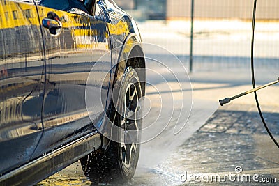 Closeup of male driver washing his car with contactless high pressure water jet in self service car wash Stock Photo