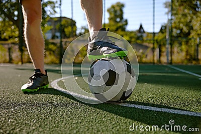 Closeup male foot in boots on soccer ball over green grass field Stock Photo