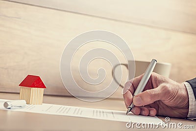 Closeup of male hand signing insurance papers, contract of house Stock Photo