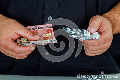 Closeup of a man with a pile of euro bills and pills in his hands Stock Photo