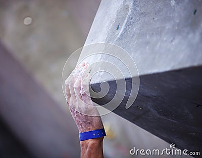 Closeup of man's hand on handhold on artificial climbing wall Stock Photo