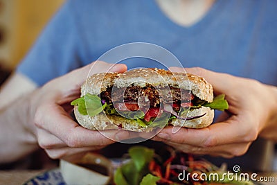 Closeup of man`s hands holding vegan chickpea and bean burger with fresh greens Stock Photo
