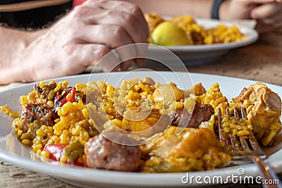 Closeup of a Man serving typical paella from Valencia (Spain) on white plates in a restaurant Stock Photo