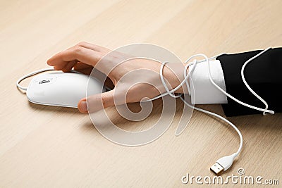 Closeup of man taking computer mouse at wooden table, hand tied with cable. Internet addiction Stock Photo