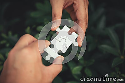 Closeup of man and woman hands connecting jigsaw puzzle together Stock Photo