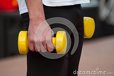 man with yellow dumbbells in hands Stock Photo
