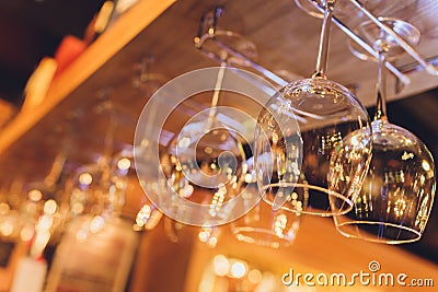 Closeup many upside down empty clear transparent crystal upturned wine glasses hanging in straight rows on brown wooden Stock Photo