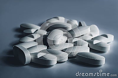 Closeup of many white prescription drugs, medicine tablets or vitamin pills in a pile - Concept of healthcare, opioids addiction Stock Photo