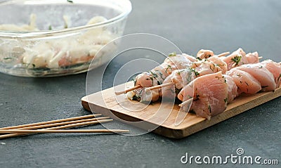 Closeup marinated shashlik from chicken meat on wooden skewer with onion on wood board, side view. Stock Photo