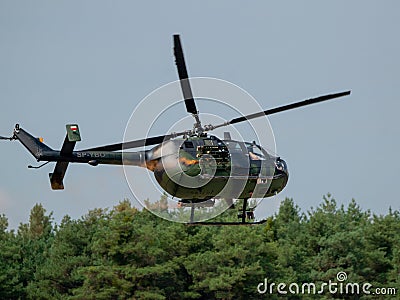 Closeup of MBB Bo105 helicopter releasing paint above green trees at an air show in Slovakia Editorial Stock Photo