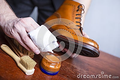 Closeup of Mens hands Polishing Leather Tanned Derby Brogue Boots. using variety of Brushes and Polishing Wax Stock Photo