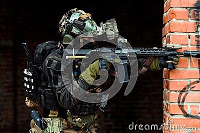 Closeup military man in black uniformaims aims at the sight machinegun. Soldier in the broken building Stock Photo