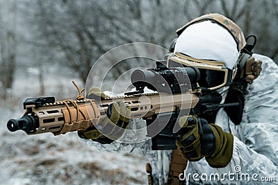 Closeup military man in white camouflage uniform with machinegun. Soldier aims of the machinegun Stock Photo