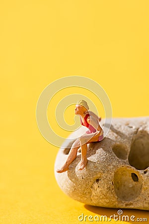 Miniature woman in swimsuit on a rock Stock Photo