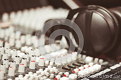 Closeup mixing console with headphones on top, faders and knobs background, artistic studio equipment concept Stock Photo