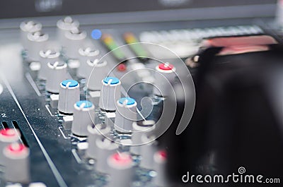 Closeup mixing console with headphones on top, faders and knobs background, artistic studio equipment concept