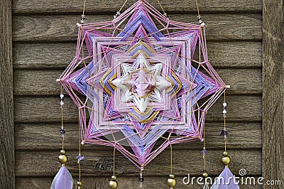 Closeup modern dreamcatcher star mandala with amethyst and peacock feathers on wooden background Stock Photo