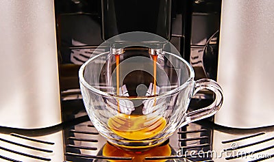 Closeup of modern fully automatic coffee maker machine outlet, one isolated transparent glass cup filling with fresh brewed cafe Stock Photo