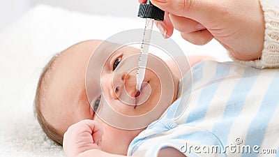 Closeup of mother giving vitamin D and K to her newborn baby son from eyedropper. Concept of babies and newborn Stock Photo