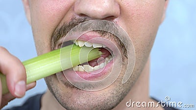 Closeup mouth. handsome mustachioed man happily eats a stalk of celery Stock Photo