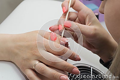 Closeup nail service mater assists cuticle removal procedure with wooden handle in salon Stock Photo