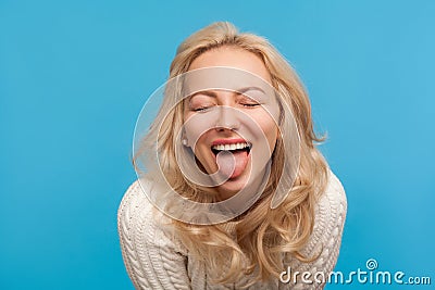 Closeup naughty playful woman with blond curly hair showing tongue at camera with closed eyes, having fun, joke Stock Photo