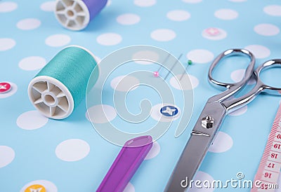 Closeup needles, thread spool, scissors, button on blue wooden Stock Photo