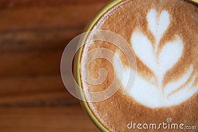 Closeup of nice latte art on a cup of coffee on a wooden surface Stock Photo