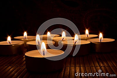 Closeup of nine candles in the dark on a wooden table Stock Photo