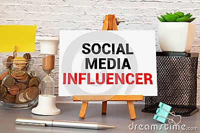 Closeup on notebook over wood table background, focus on wooden blocks with letters making Social Media Influencer text Stock Photo