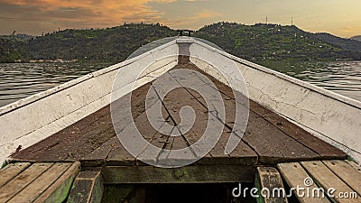 Closeup of an old rough wooden boat on the water surrounded by hills during the sunset Stock Photo