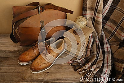 closeup old things, stack of vintage books, globe, shoes, leather military satchel on table, checkered grandmother's plaid, Stock Photo