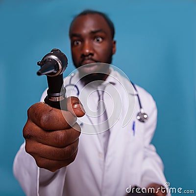 Closeup of otoscope in hand of african american doctor with funny face expression Stock Photo