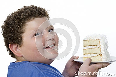 Closeup Of An Overweight Boy Holding Large Slice Of Cake Stock Photo